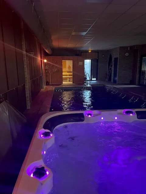 Jacuzzi intérieur aux lumières violettes près de la piscine